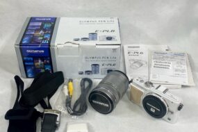 OLYMPUS PEN Lite E-PL6のカメラセット。箱や説明書、標準レンズと望遠レンズ、各種ケーブルやアクセサリーなどの付属品が整然と並べられている。
