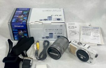 OLYMPUS PEN Lite E-PL6のカメラセット。箱や説明書、標準レンズと望遠レンズ、各種ケーブルやアクセサリーなどの付属品が整然と並べられている。
