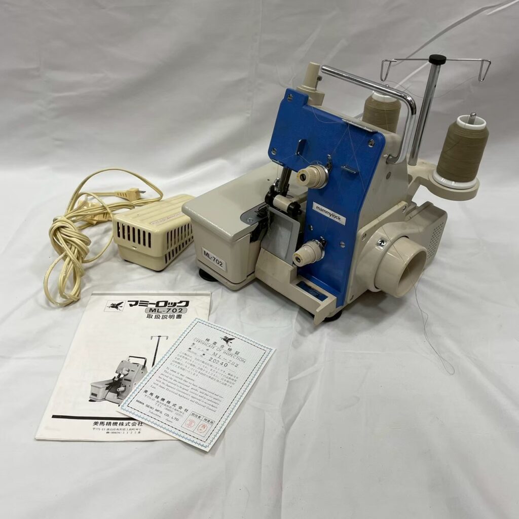 mammylock ML-702のロックミシン本体と付属品（説明書・保証書）が揃って並べられている写真。大阪市での買取品。