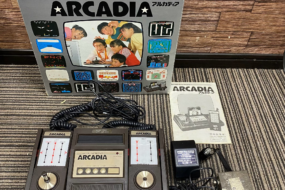 BANDAI ELECTRONICS ARCADIA本体とコントローラー、ACアダプター、マニュアル、外箱がすべて揃っている状態の写真。