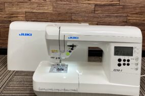 大阪市で出張買取したJUKIのコンピューターミシン「F250-J」の写真。白を基調とした本体に液晶ディスプレイと各種操作ボタンが搭載されたモデル。